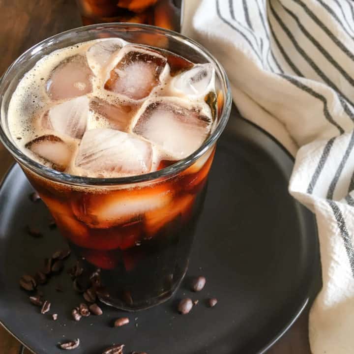 two cups of cold brew coffee with ice and coffee beans