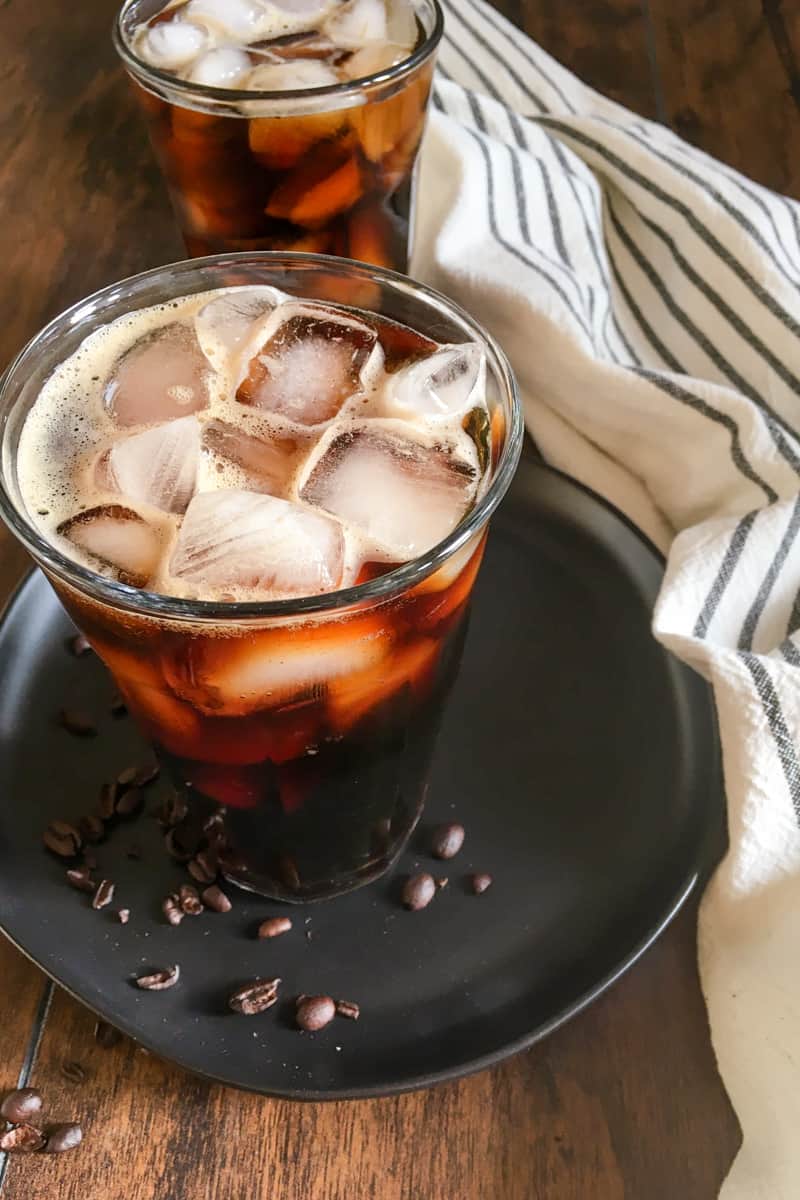 two cups of cold brew coffee with ice and coffee beans