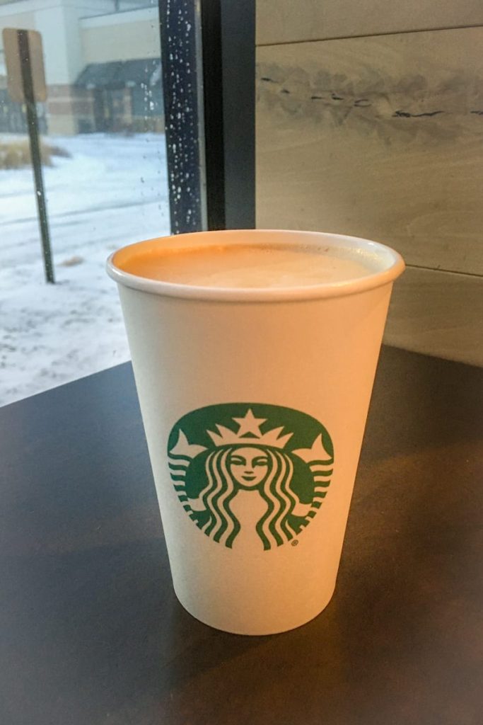 hot starbucks latte in white cup with lid off