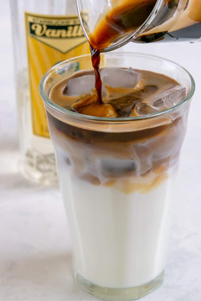 Espresso being poured on top of milk and ice layer.