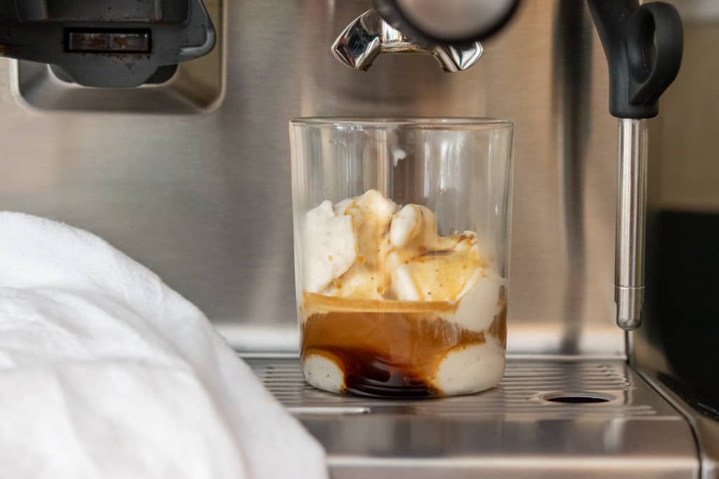 Affogato in cup sitting on espresso machine tray.