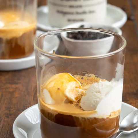 Affogato in two cups with pint of vanilla gelato in background.