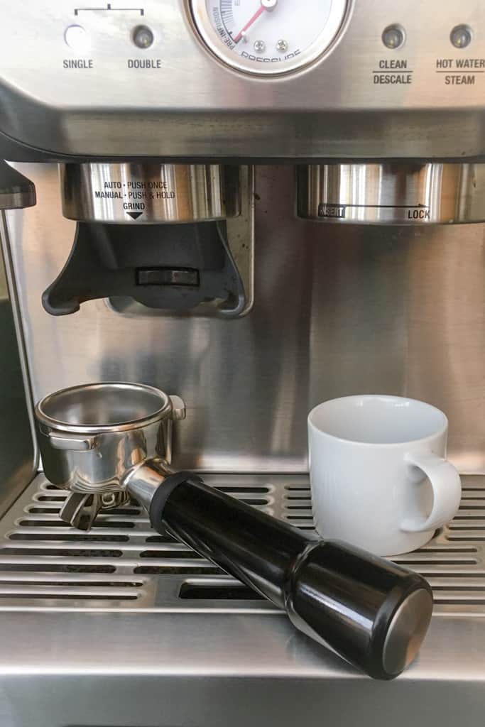 Espresso machine with portafilter and white cup.