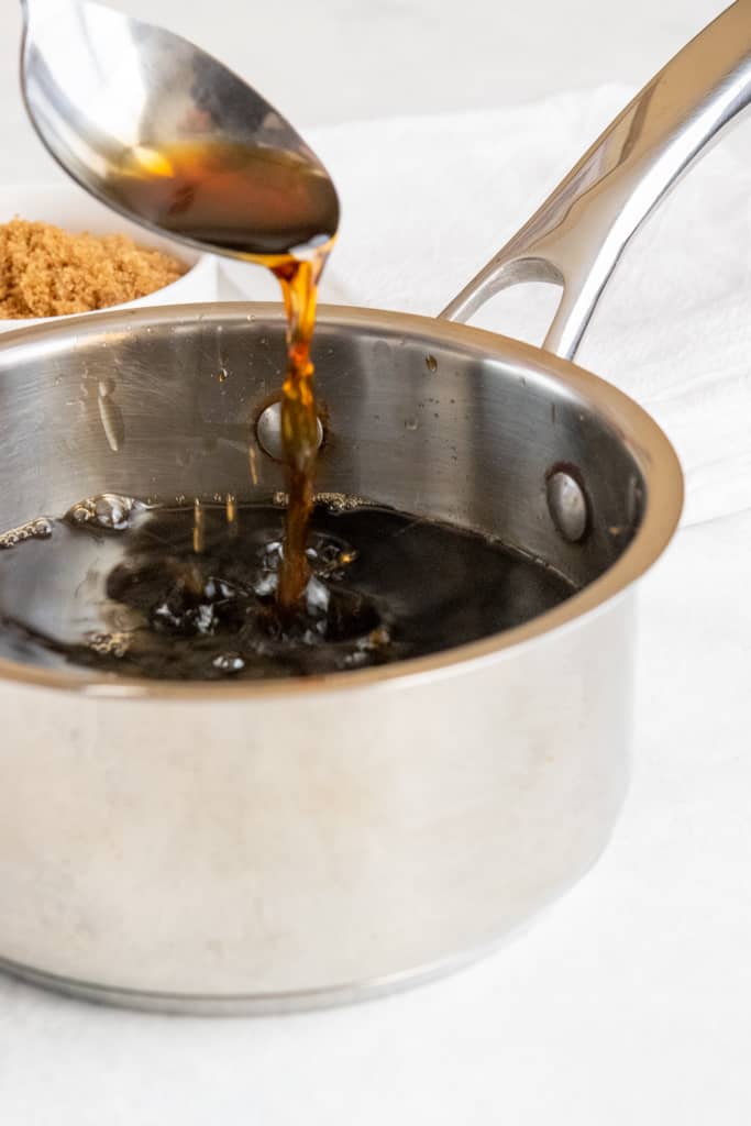 A spoonful of simple syrup dripping into pan full of syrup.