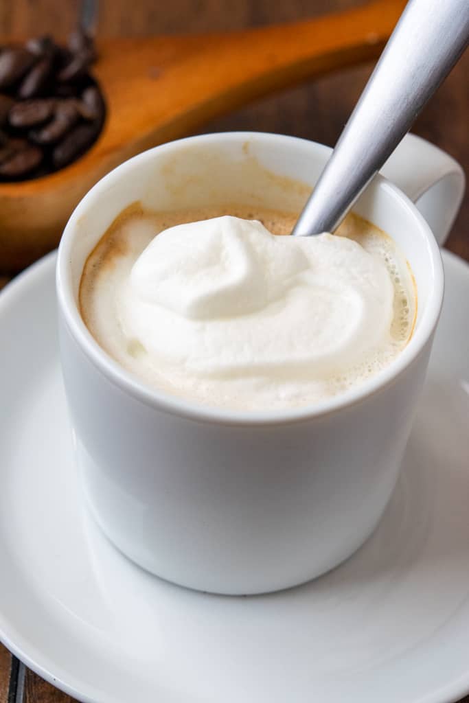 Espresso con panna with spoon inside cup.