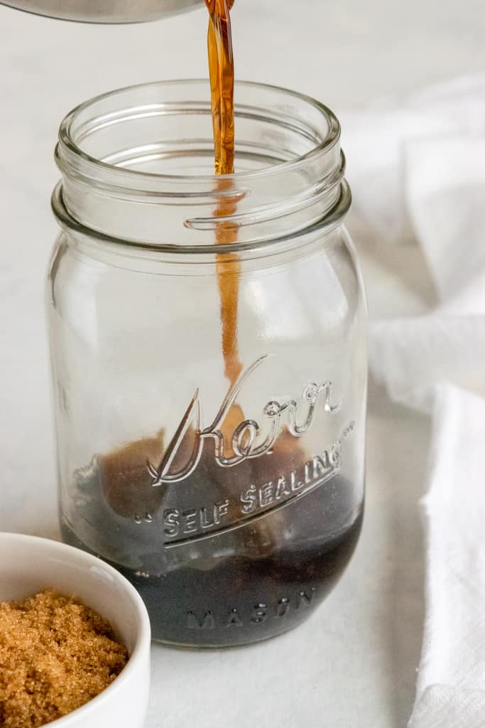 Pouring brown sugar simple syrup into mason jar.