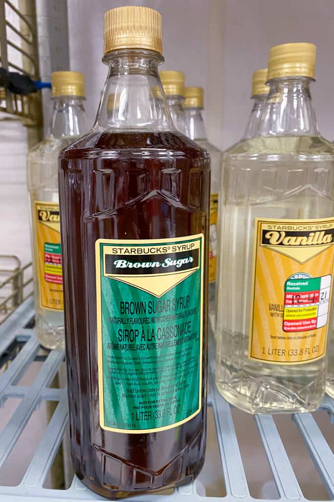 Bottle of Starbucks brown sugar syrup on shelf in front of bottles of vanilla syrup.