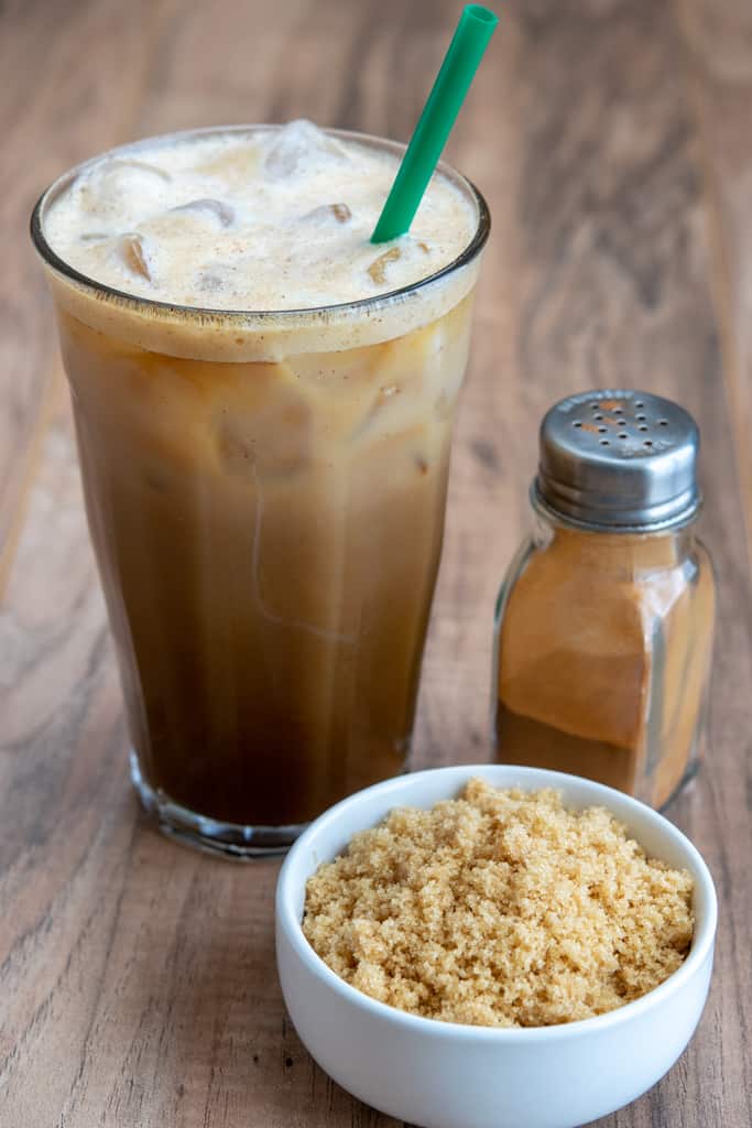 Starbucks copycat Iced Brown Sugar Oat Milk Shaken Espresso and bowl of sugar and bottle of cinnamon.