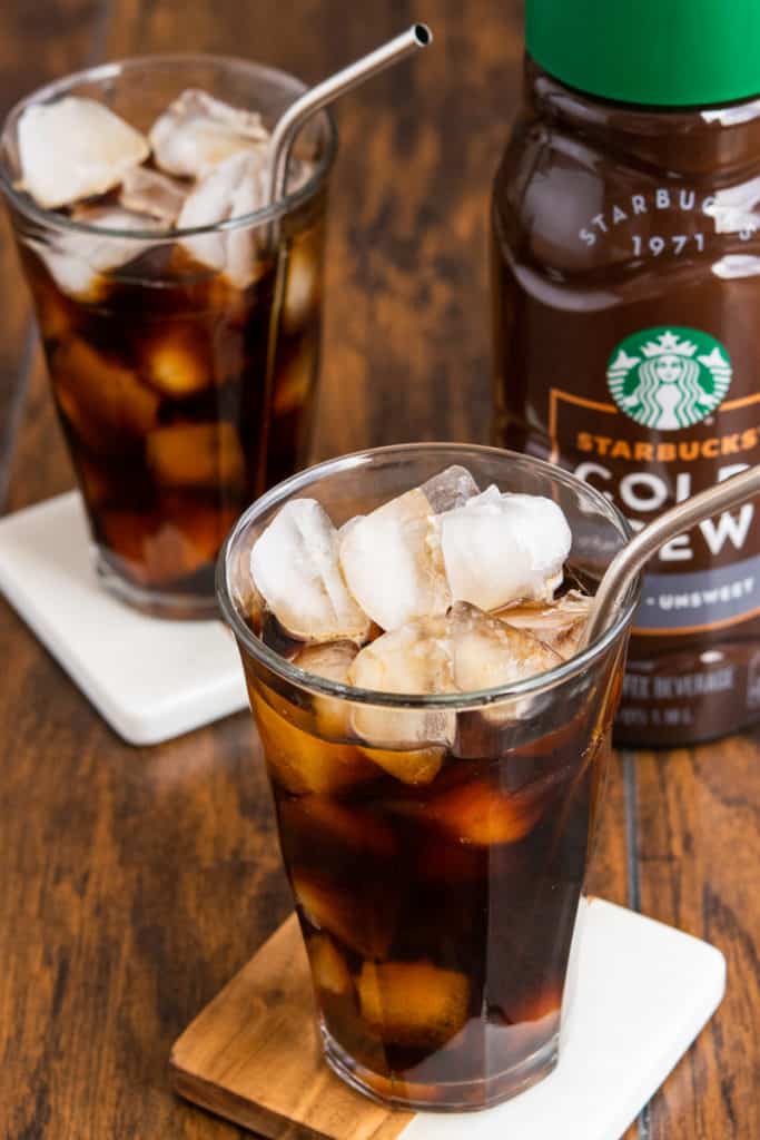 Starbucks cold brew and two glasses filled with ice and cold brew coffee.
