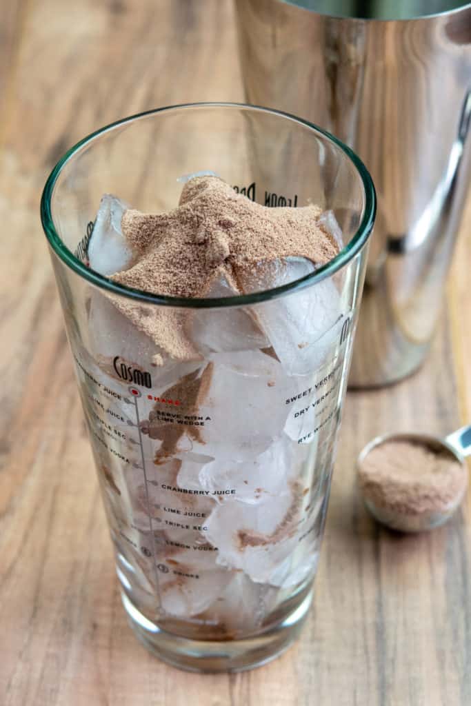 Chocolate malted milk scooped on top of ice in drink shaker.