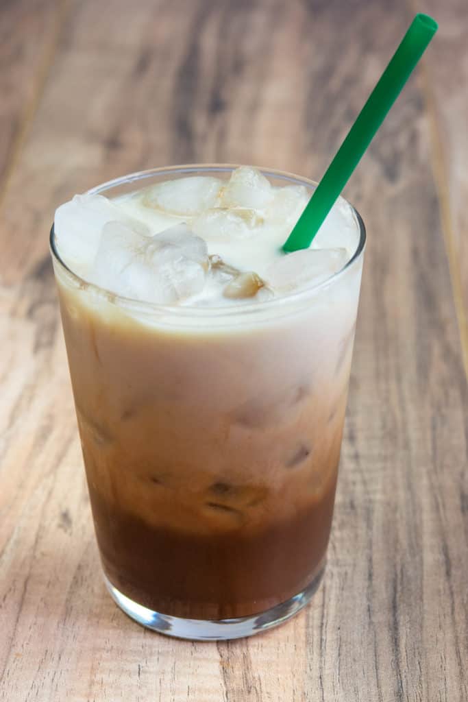 Homemade chocolate almond milk shaken espresso in glass with green straw.