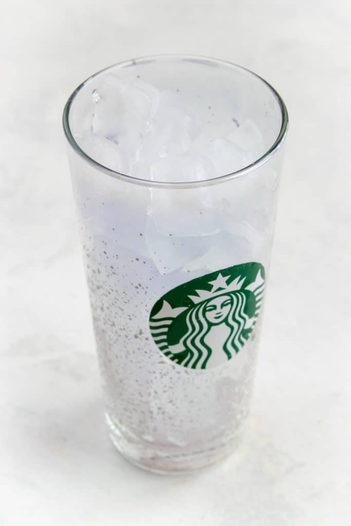 Making iced shaken espresso by filling glass with ice.