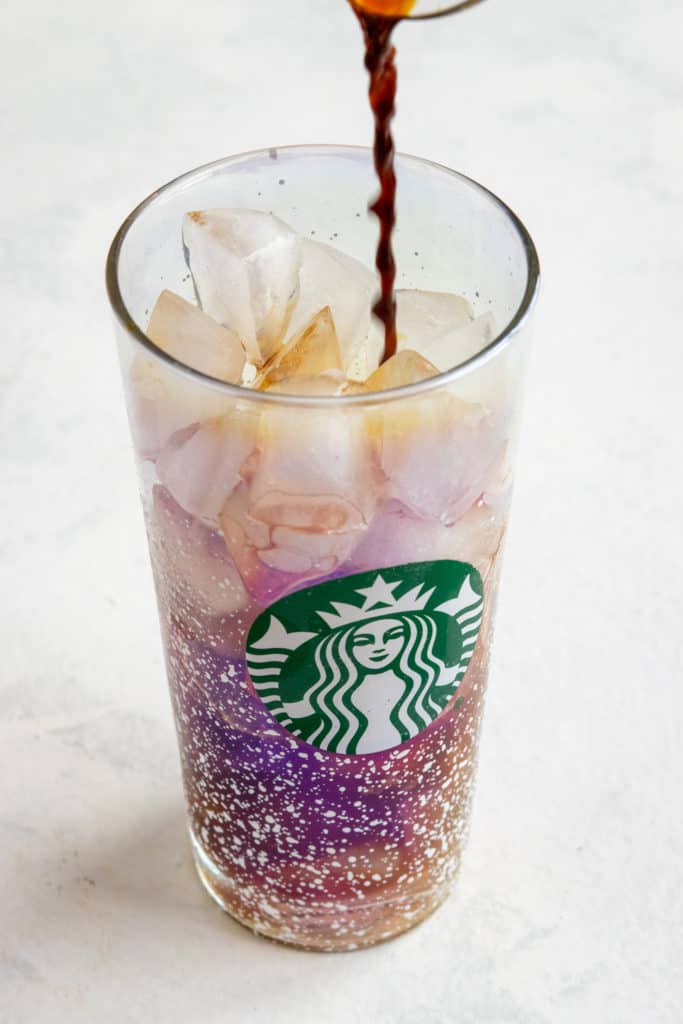 Pouring espresso into glass with ice to make a homemade iced shaken espresso.