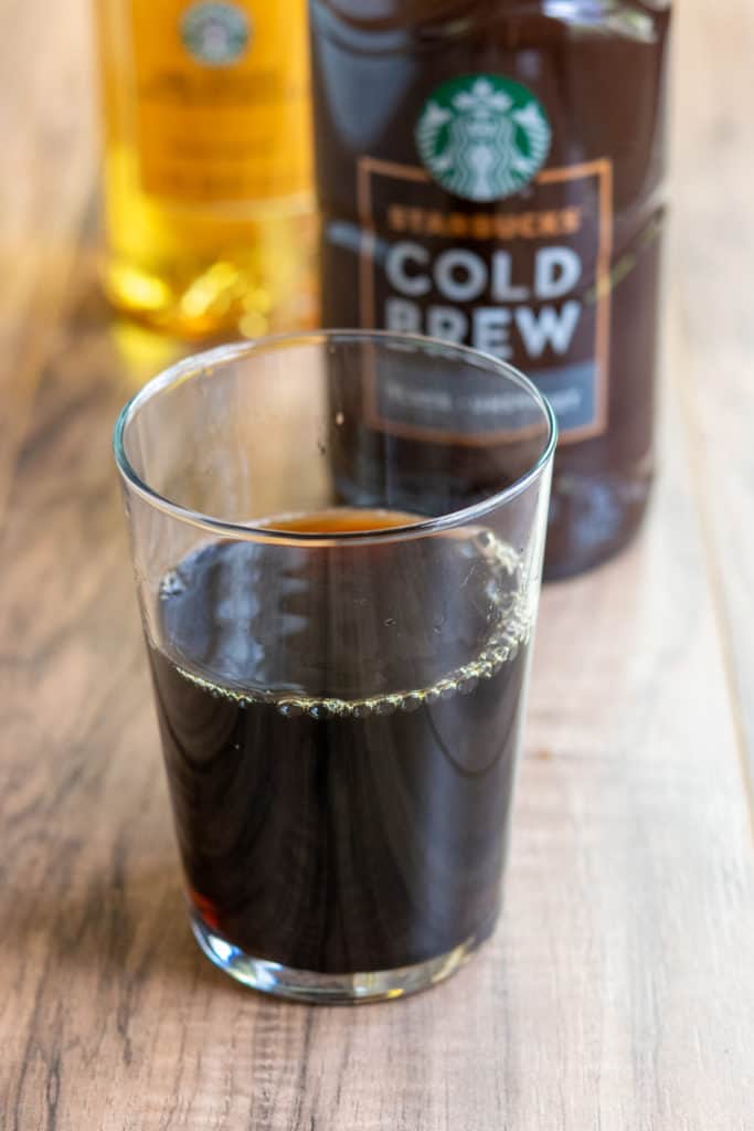 Cold brew coffee in a cup mixed with caramel syrup.