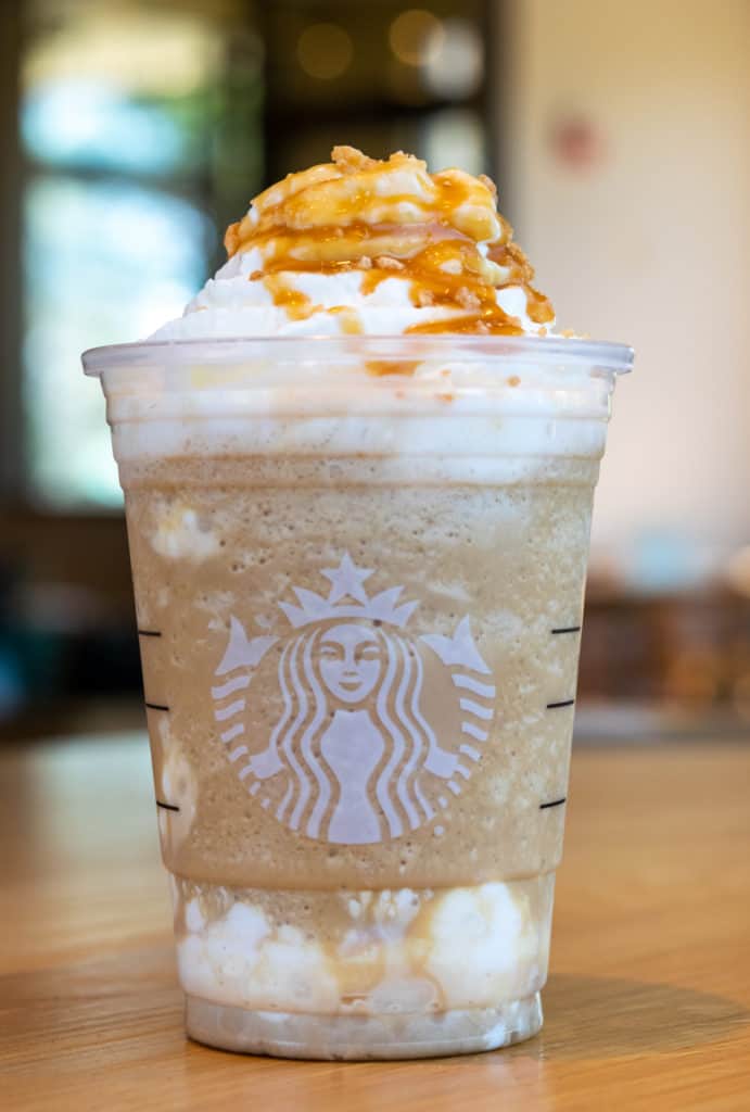 Starbucks Caramel Ribbon Crunch Frappuccino blended beverage on table inside Starbucks.