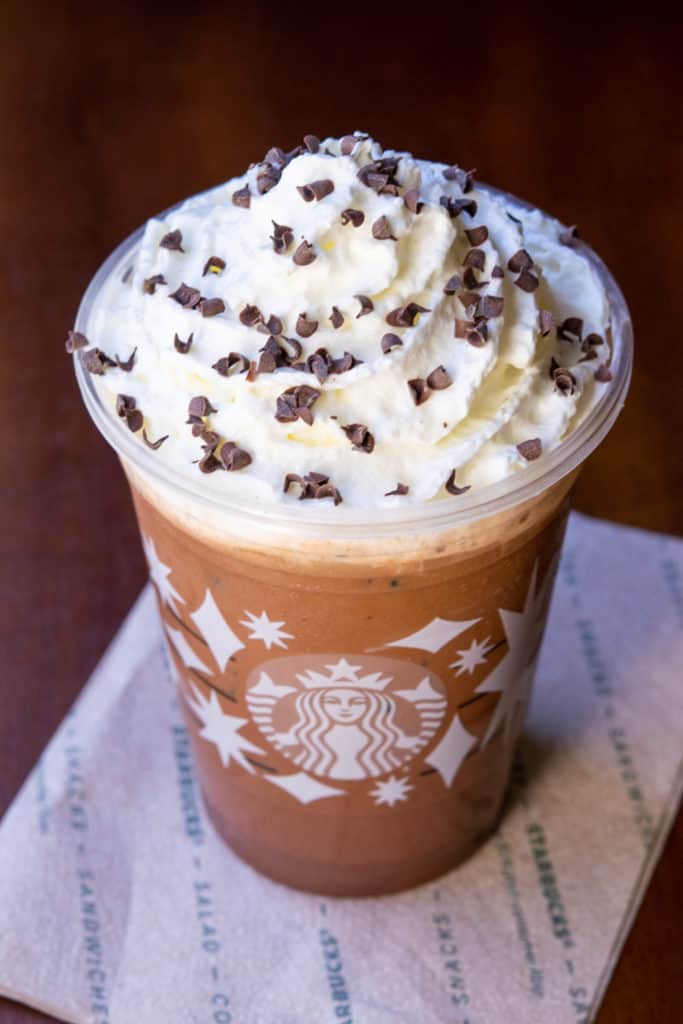 Starbucks Iced Peppermint Mocha with whipped cream and dark chocolate curls in holiday cup.