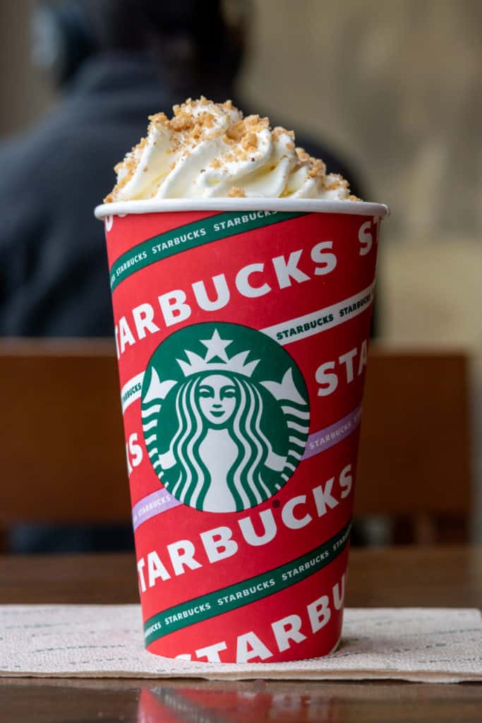 Starbucks Chestnut Praline Latte in red  cup and topped with whipped cream.