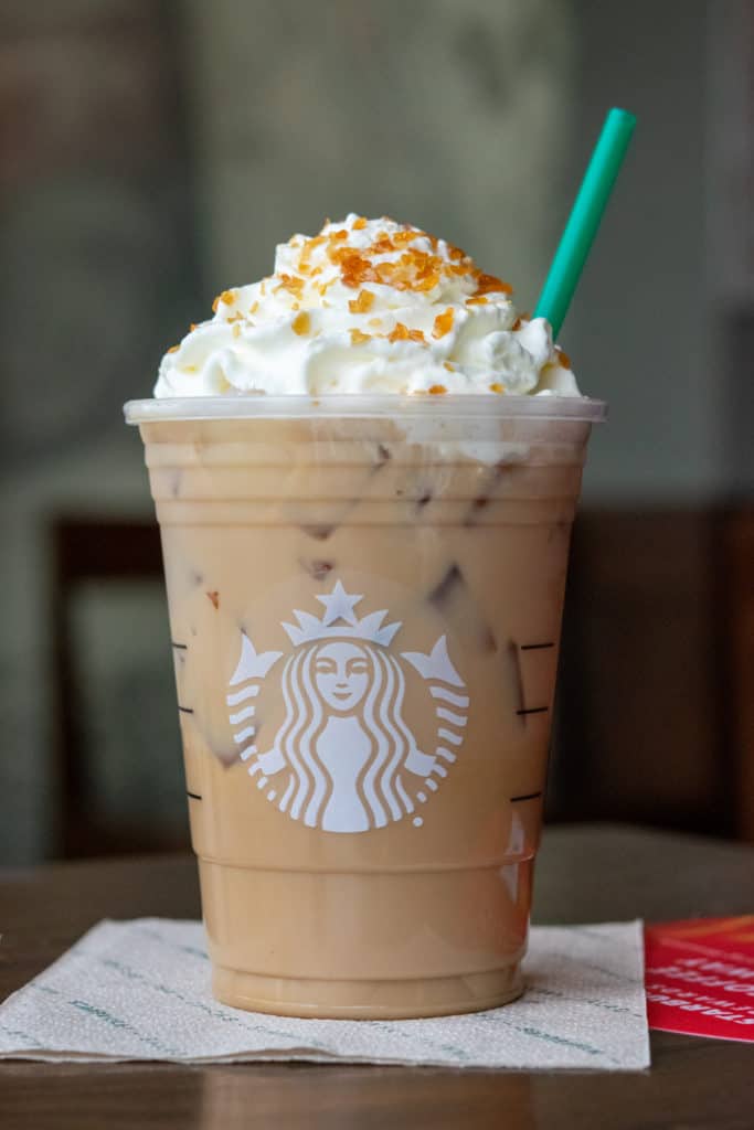 Starbucks Caramel Brulee Latte with green straw.