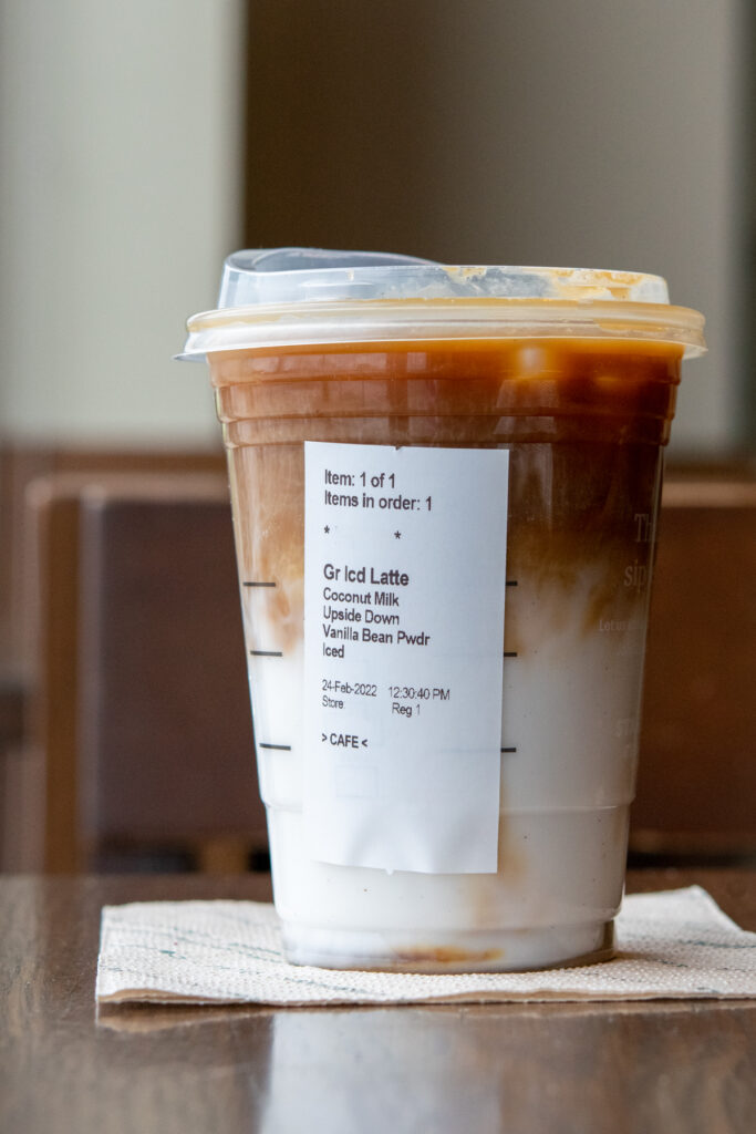 A grande upside down iced latte with vanilla bean powder and coconutmilk with the Starbucks order sticker on the cup.