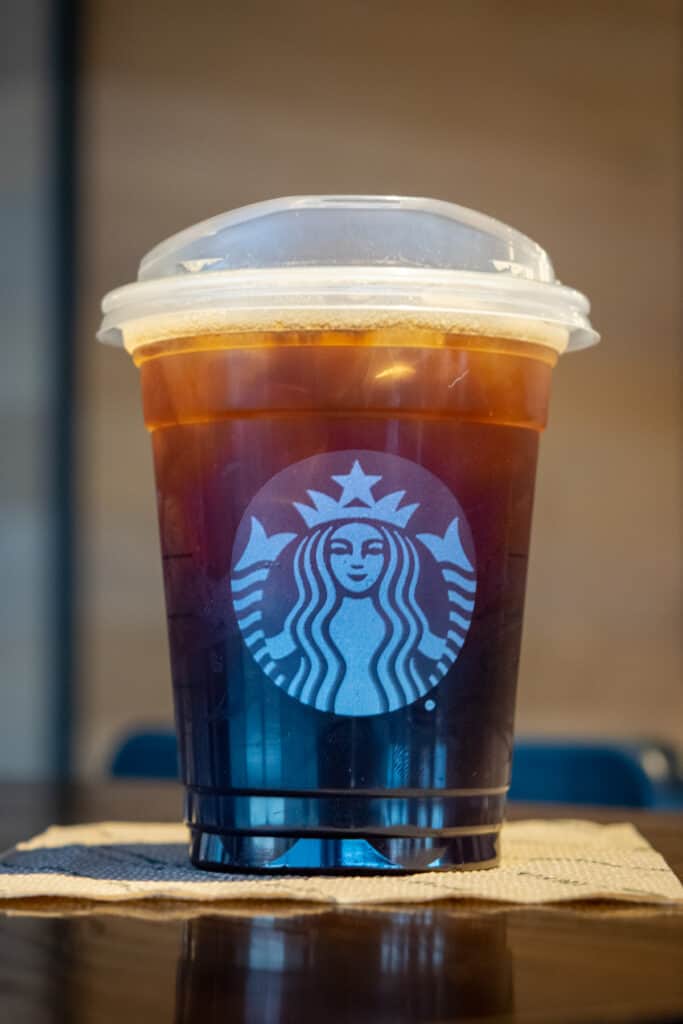 An iced Americano in a grande size Starbucks cup.