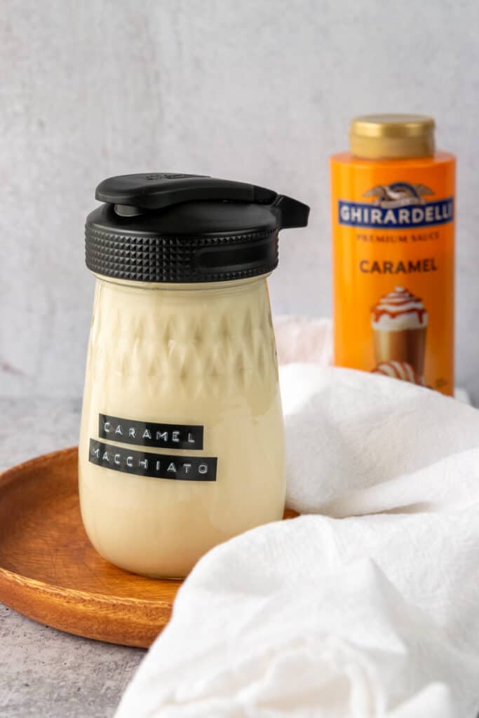 Jar full of homemade caramel macchiato creamer and a bottle of Ghiradelli premium caramel sauce.