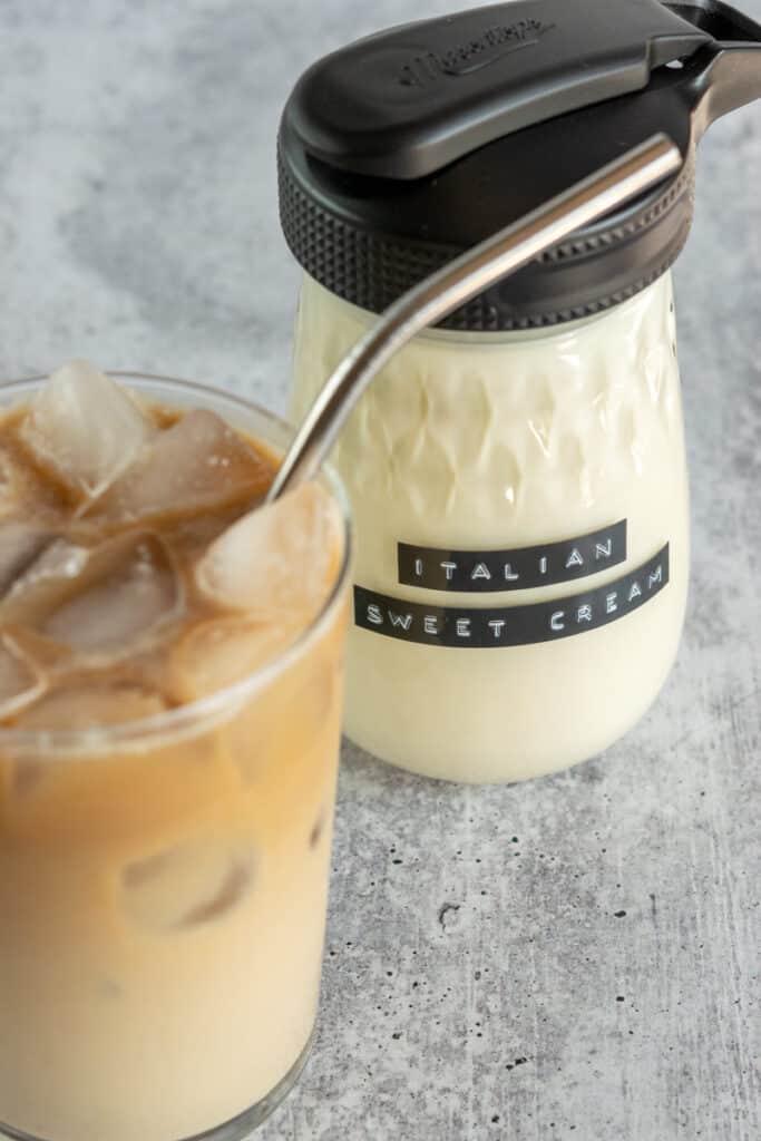 An iced coffee with creamer in it, sitting in front of a bottle of homemade Italian Sweet Cream creamer.