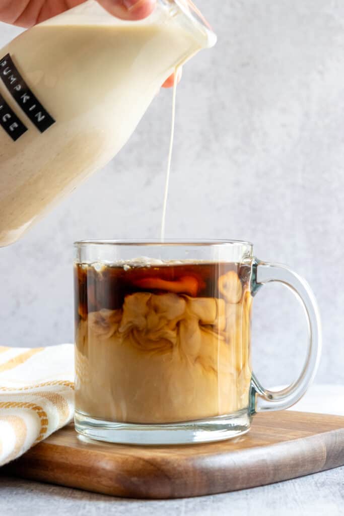 Homemade pumpkin spice coffee creamer being poured into a cup of hot coffee.