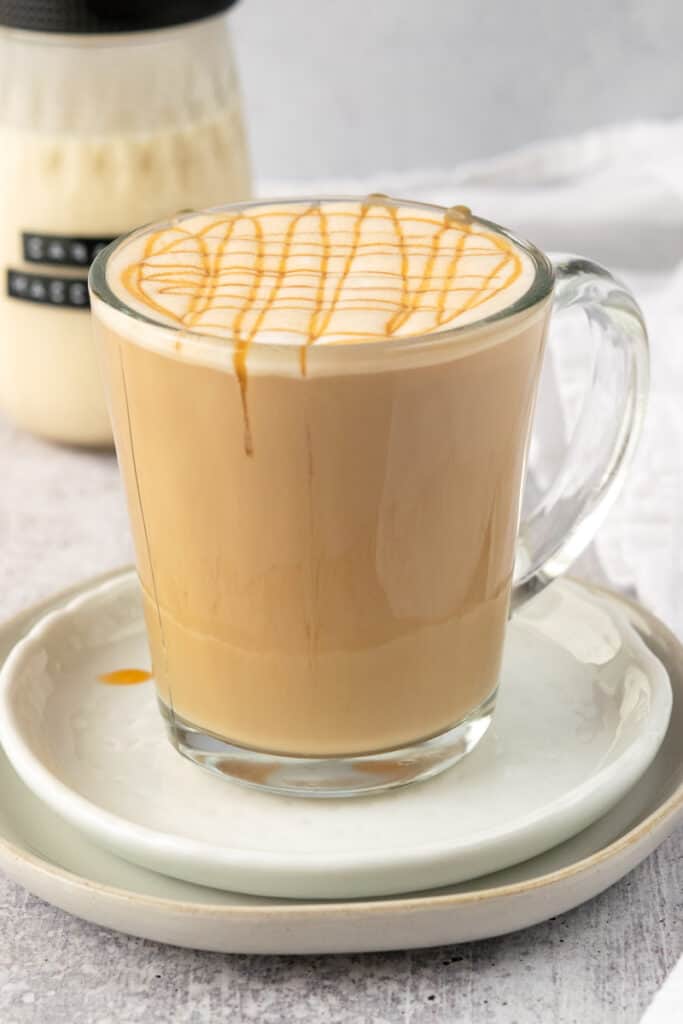 A homemade caramel macchiato with caramel drizzle on top, and a jar of caramel macchiato coffee creamer.