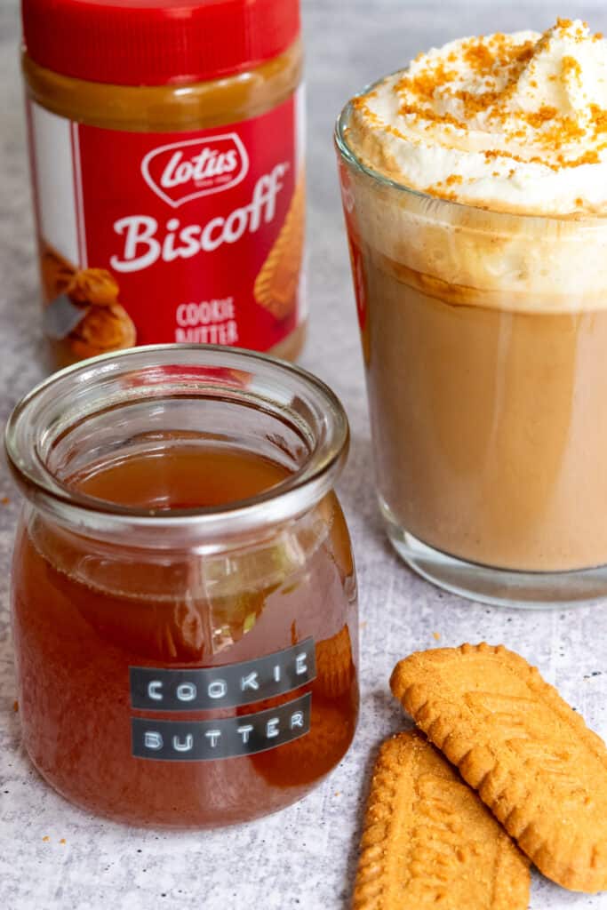 Jar of Biscoff cookie butter, jar of homemade cookie butter syrup, two Biscoff cookies and a homemade cookie butter latte.