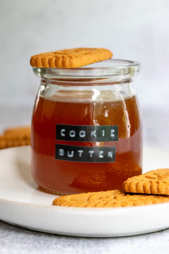 Jar of homemade cookie butter syrup with Lotus Biscoff cookies on a plate.