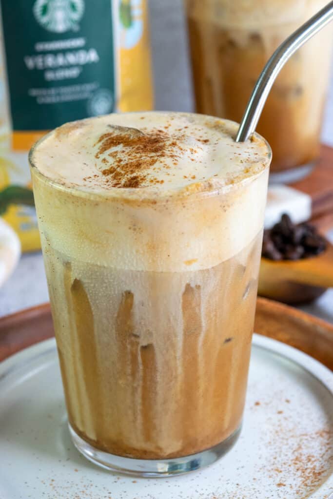 A bag of Starbucks Veranda roast coffee beans and two brown sugar shaken espresso beverages made at home that have a thick layer of pumpkin cold foam on top.