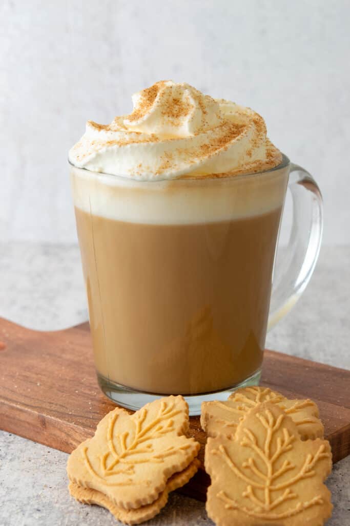 Homemade maple latte topped with whipped cream and cinnamon and three maple syrup cookies.