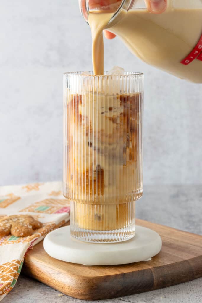 Bottle of homemade gingerbread creamer being poured into an iced gingerbread latte.