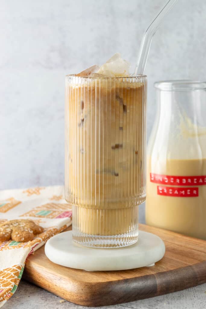 An iced gingerbread latte, gingerbread cookie and bottle of homemade gingerbread coffee creamer.