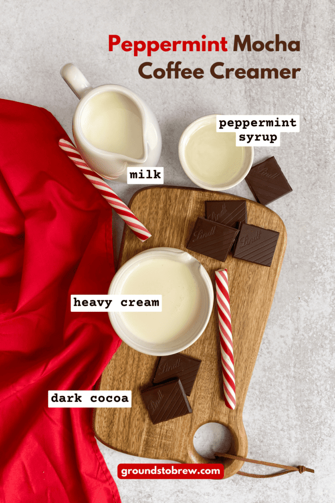 All the recipe ingredients to make homemade peppermint mocha creamer in small bowls with peppermint sticks and cocoa bar on a cutting board.