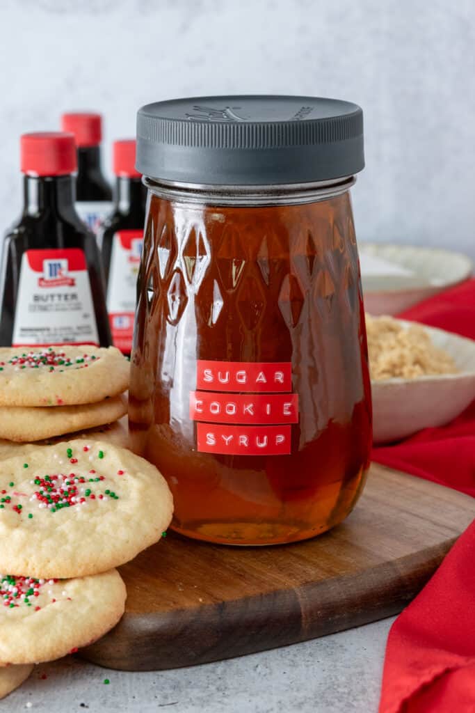 Bottles of vanilla, butter and almond extracts, jar of copycat Starbucks sugar cookie syrup, and sugar cookies.