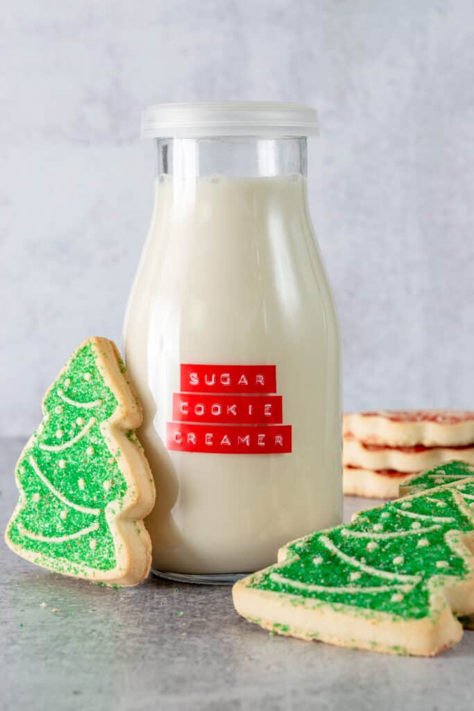 Christmas sugar cookies next to a bottle of homemade sugar cookie creamer.