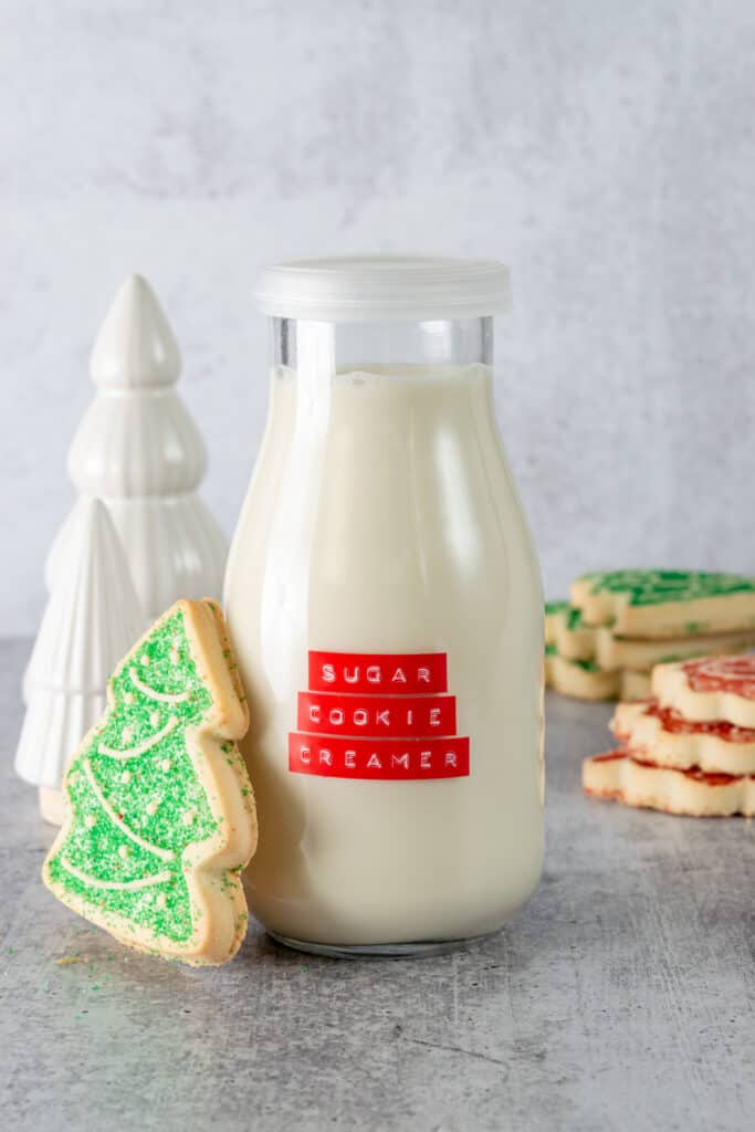 Homemade sugar cookie coffee creamer iwht Christmas tree sugar cookie next to bottle of creamer.