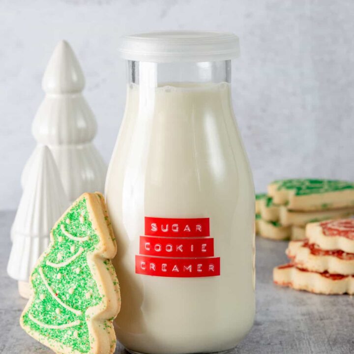 Homemade sugar cookie coffee creamer iwht Christmas tree sugar cookie next to bottle of creamer.