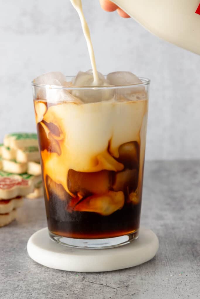 Pouring creamer into an iced sugar cookie latte.