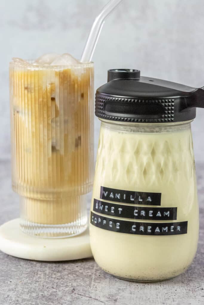 Bottle of homemade vanilla sweet cream coffee creamer and an iced coffee drink mixed with the creamer.