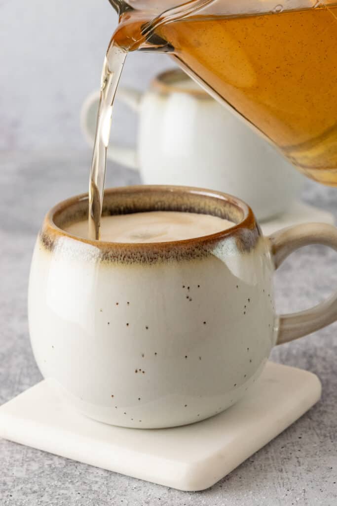 Homemade vanilla syrup being poured into a cup of coffee.