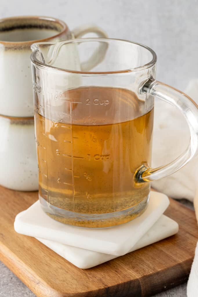 Glass measuring cup full of homemade vanilla bean syrup with seeds floating in it.
