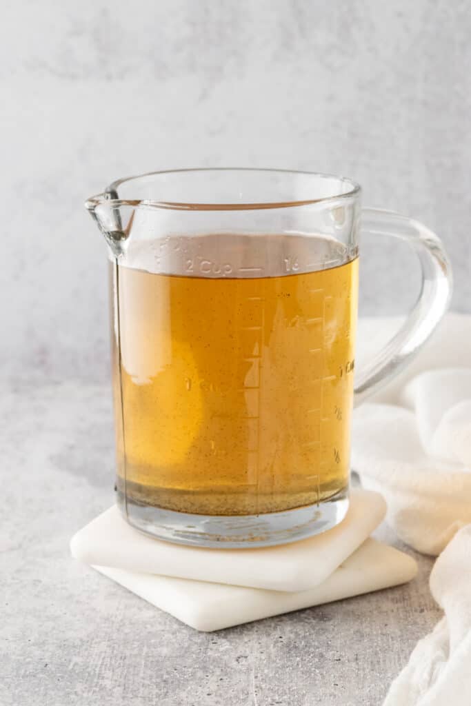 Homemade vanilla simple syrup for drinks in a glass jar sitting on top of two white coasters.