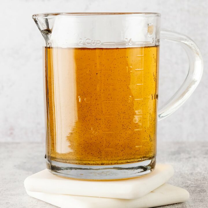 Homemade vanilla bean syrup in a glass measuring cup with spout.