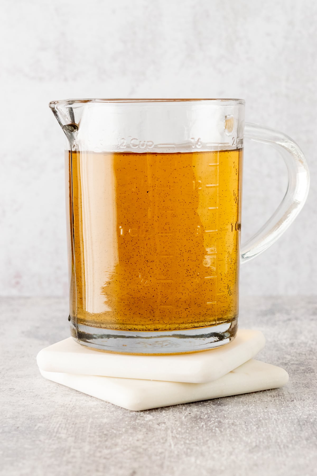 Homemade vanilla bean syrup in a glass measuring cup with spout.