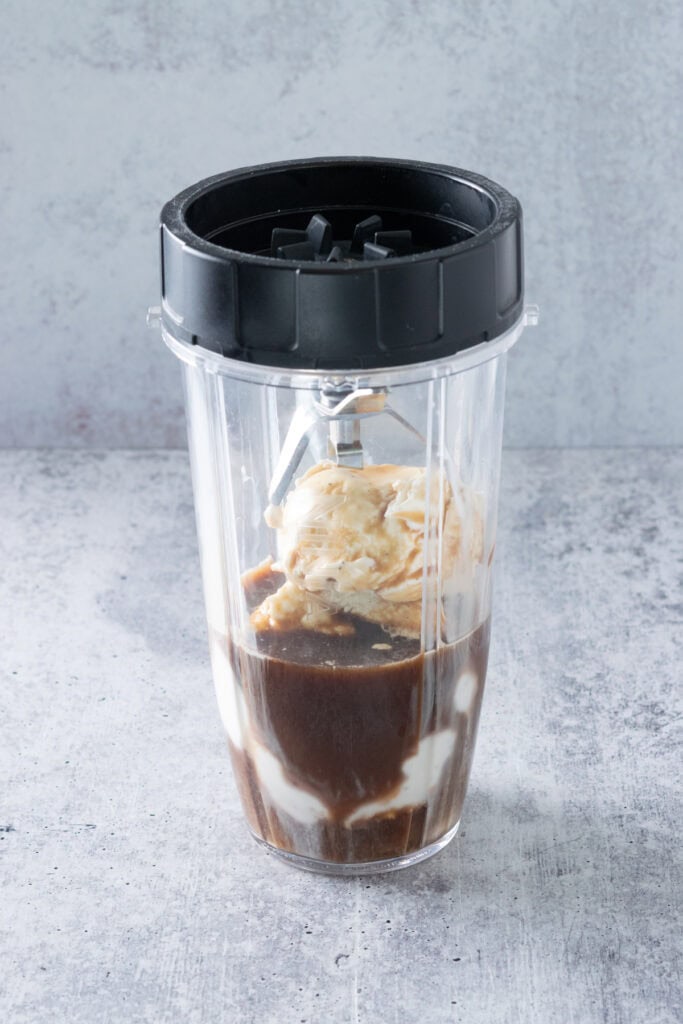 The blender blades screwed on top of the blender cup which has vanilla ice cream and coffee in it.